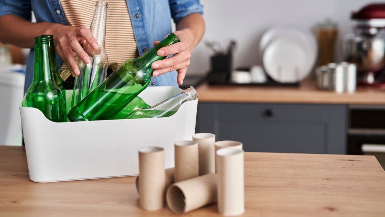 Un hombre separa botellas y el cartón del papel higiénico. Canva 