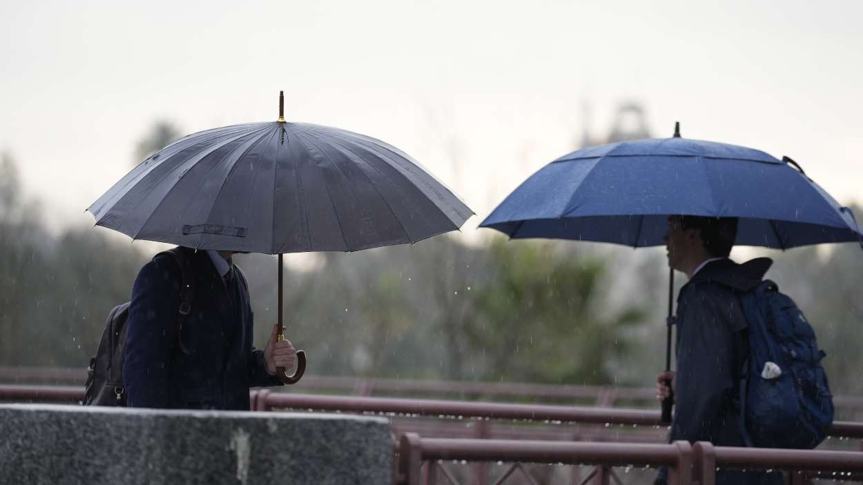 Personas se protegen de la lluvia con un paraguas. EP